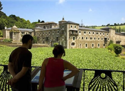 Dos turistas consultando un panel frente al monasterio de Samos (Lugo) en el camino de Santiago