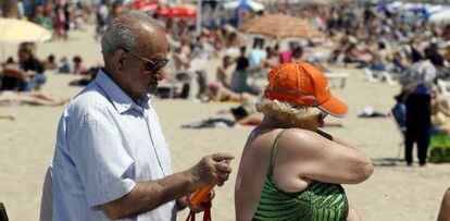 Una pareja de jubilados se dirige a la playa de El Postiguet, en Alicante