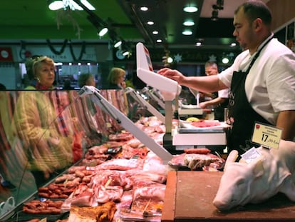 Un carnicero atiende a sus clientes en un mercado de Madrid.