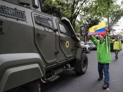 Un hombre exhibe una bandera mientras pasa un vehículo blindado donde es trasladado el exvicepresidente ecuatoriano Jorge Glas.