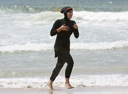 Una mujer ataviada con un <i>burkini</i> sale del mar<i>.</i>