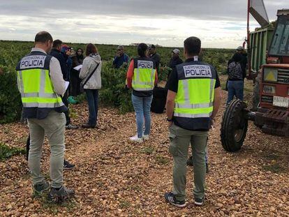 Agentes de la Policía Nacional junto a varios jornaleros en Villanueva de Duero (Valladolid).