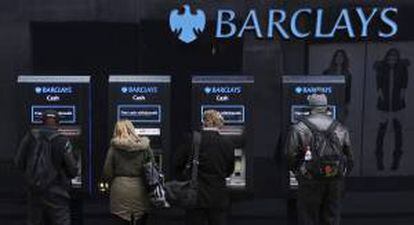 Varios clientes utilizan cajeros automáticos de una sucursal del banco británico Barclays en Londres.