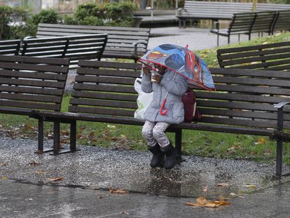 Una niña protegida con un paraguas merienda en la plaza de Europa, en Gijón, el pasado 1 de diciembre.