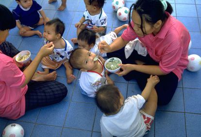 Dos mujeres trabajadoras alimentan los niños en Vienping, un orfanato en Chiang Mai (Tailandia) donde un gran porcentaje de los niños son portadores del VIH.