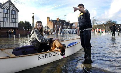 Una niña y un perro en una barca intentan cruzar una calle inundada de Berkshire. 