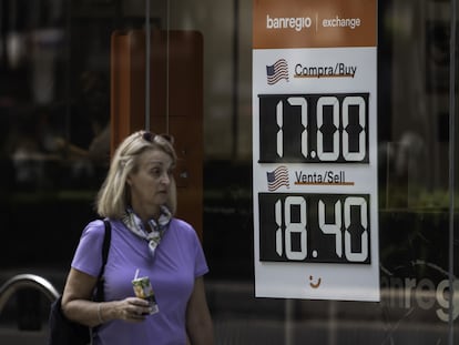 Una mujer camina junto a un banco que muestra los precios del dólar  en Ciudad de México, en mayo pasado.