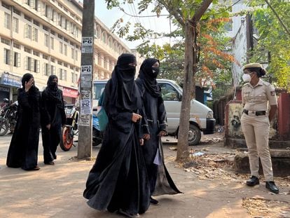 Alumnas con 'hiyab' llegan a clase mientras una mujer policía monta guardia en el exterior de una escuela pública femenina tras la reciente prohibición del hiyab, en la ciudad de Udupi, en el estado sureño de Karnataka, India, el pasado 16 de febrero.