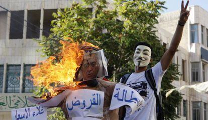 Un manifestante, junto a un figura de Salam Fayad quemada.