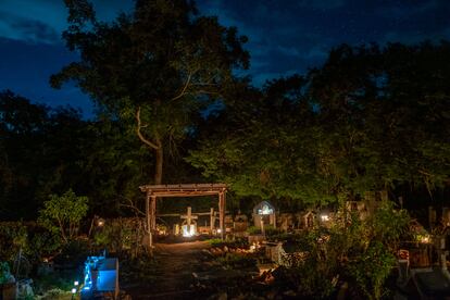 Tras la ceremonia decae la luz del sol y las velas iluminan el cementerio de la comunidad maya de Xocén, en Yucatán (México), el primero de noviembre de 2021.