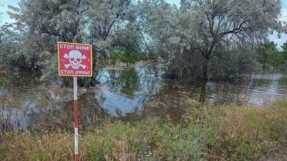 Una señal advierte del peligro de minas en una zona inundada.