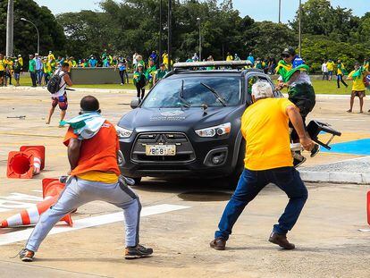 TOPSHOT - Supporters of Brazilian former President Jair Bolsonaro attack a vehicle of the Military Police during clashes outside Planalto Presidential Palace in Brasilia on January 8, 2023. - Hundreds of supporters of Brazil's far-right ex-president Jair Bolsonaro broke through police barricades and stormed into Congress, the presidential palace and the Supreme Court Sunday, in a dramatic protest against President Luiz Inacio Lula da Silva's inauguration last week. (Photo by Sergio Lima / AFP)