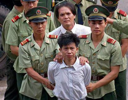 Wang Shijian (delante), de China, y Wong Tin-soong, de Hong Kong, son conducidos por policías chinos a un estadio en Shenzhen para escuchar el anuncio público de su sentencia a la pena de muerte por tráfico de drogas