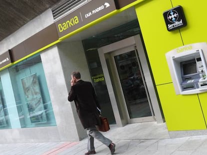 Un hombre caminando delante de una oficina de Bankia