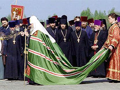 Un ayudante lleva la capa del patriarca de la Iglesia ortodoxa rusa, Alejo II, durante la bendición de un templo.