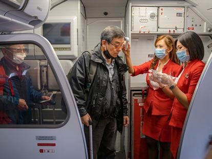 Dos azafatas comprueban la temperatura de pasajeros en en un embarque en el aeropuerto de Incheon, Corea del Sur