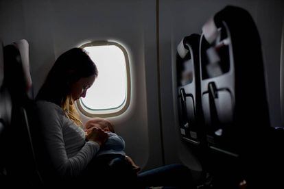 Una mujer amamanta a su bebé en un avión.