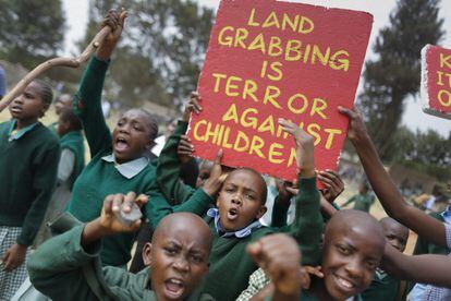 Estudiantes kenianos muestran un cartel con el mensaje "La apropiación de tierras es violencia contra los niños" durante una protesta en el patio de recreo de una escuela de Primaria en Nairobi (Kenia) en la que al menos tres menores resultaron heridos.