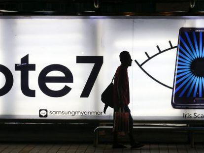 Un hombre camina junto a una parada de autob&uacute;s en la que aparece una publicidad del Galaxy Note 7 de Samsung.