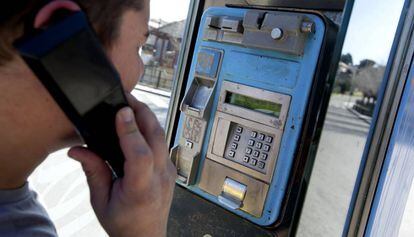 Un joven utiliza una cabina de teléfono