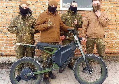 Ukrainian soldiers pose next to one of the Eleek electric motorcycles sent to the front.