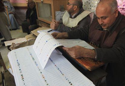 Un hombre lee la papeleta con todos los candidatos en un mesa electoral en El Cairo.