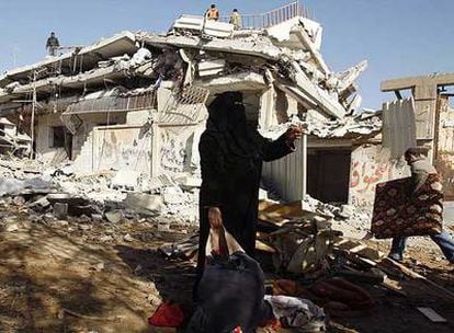 Una mujer palestina reúne lo poco que pudo salvar tras la destrucción de su casa en el poblado de Rafah
