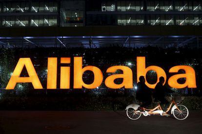 Un tándem ciclista pasa por delante del logotipo de Alibaba en Hangzhou (China)