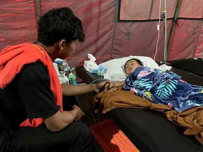 Salman Alfarisi, junto a su hermano Azka, de 6 años, que sobrevivió después de estar atrapado en las ruinas durante dos días después del terremoto del lunes, en una tienda de campaña de emergencia fuera del hospital en Cianjur, Indonesia,  23 de noviembre de 2022. 