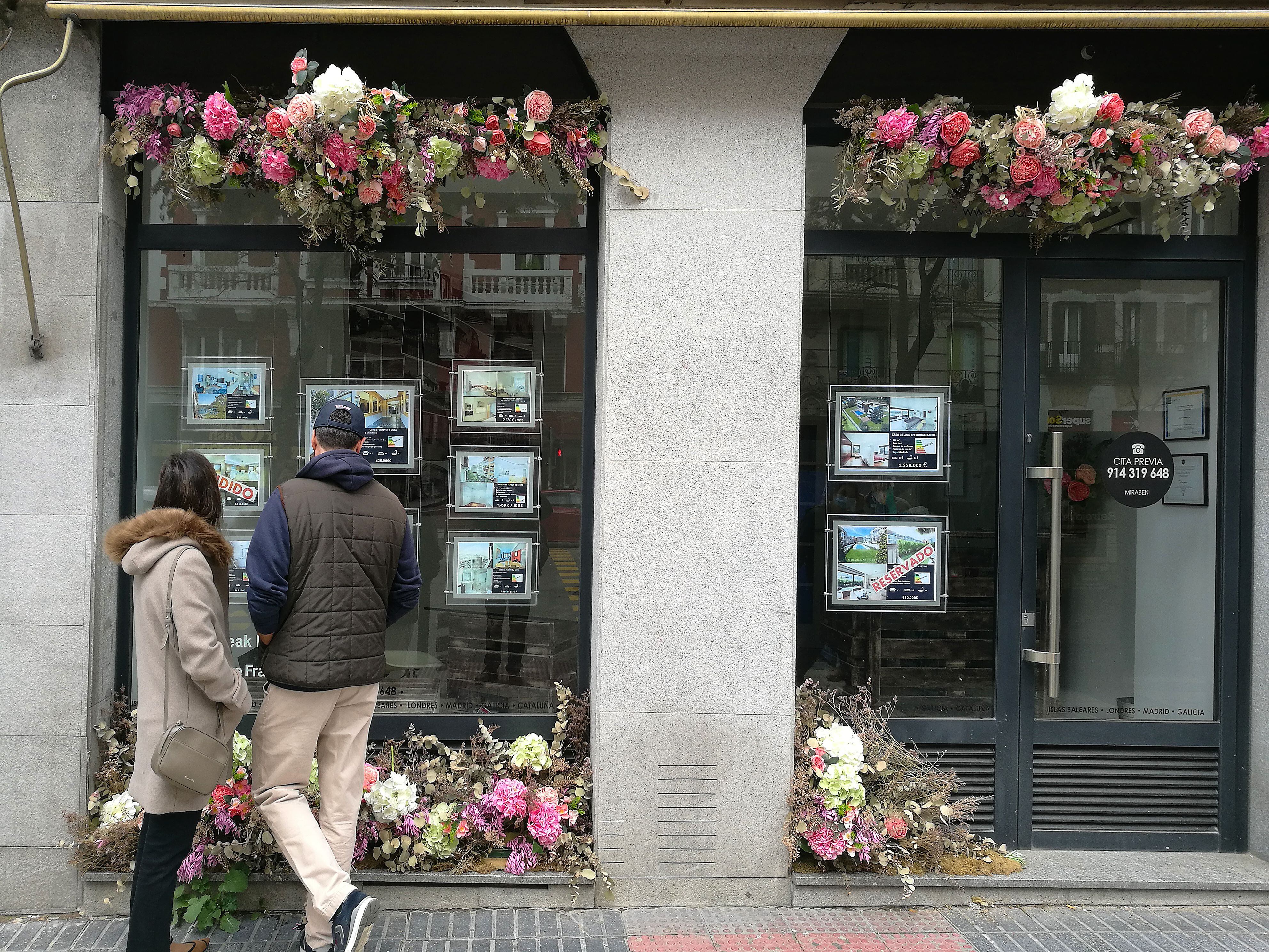 Una pareja ve las ofertas de apartamentos en el escaparate de una inmobiliaria en Madrid en 2021. 
