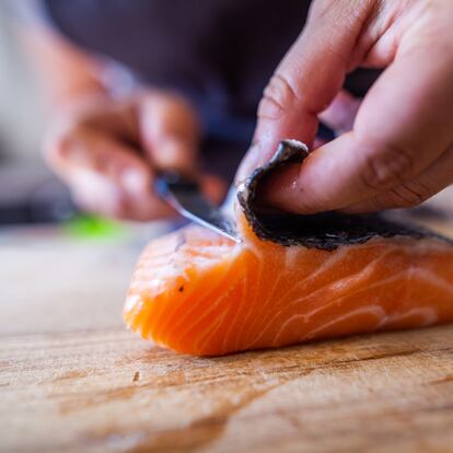 Un cocinero quita la piel a un lomo de salmón.