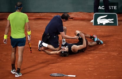Alexander Zverev se lamenta en el suelo tras la torcedura de tobillo, ante la atenta mirada de Rafael Nadal.