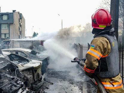 Un bombero apaga las llamas de un vehículo alcanzado por fragmentos de un misil, este jueves en Kiev.