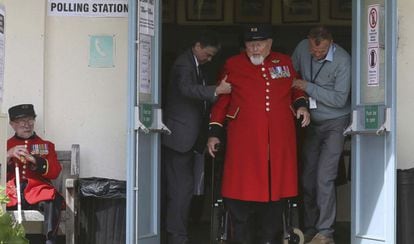 Un exmiembro del Ejercito británico, pensionista del Hospital Real de Chelsea, recibe ayuda para poder salir del centro de votación.