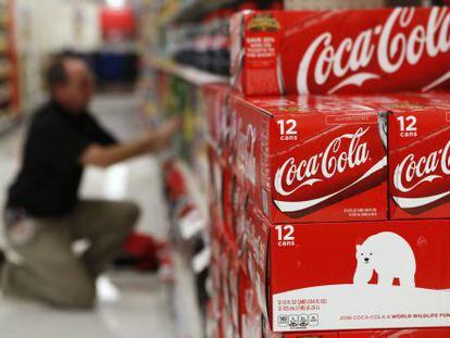 Un hombre organiza cajas de Coca-Cola en un supermercado