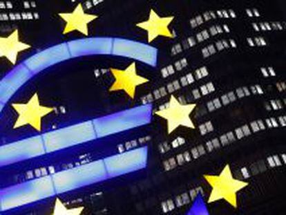 La foto muestra un signo de euro iluminado frente a la sede del Banco Central Europeo.