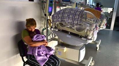 Irma Castro abraza a un bebe junto a una incubadora, en la sala de cuidados intermedios de la Maternidad provincial de Córdoba (Argentina), el 14 de enero de 2024.
