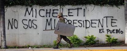 Un soldado pasa ante una pintada contraria al autoproclamado presidente de Honduras, Roberto Micheletti, en los alrededores de la Casa Presidencial en Tegucigalpa.