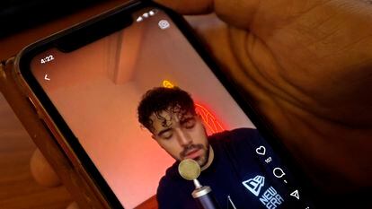 Un hombre ve en un móvil un vídeo de Shervin Hajipour cantando 'Baraye'.