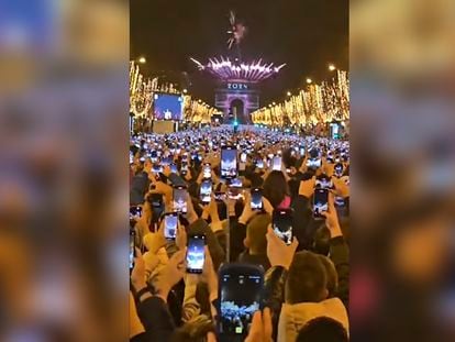 Miles de ciudadanos graban con sus móviles el espectáculo de Nochevieja en los Campos Elíseos de París.