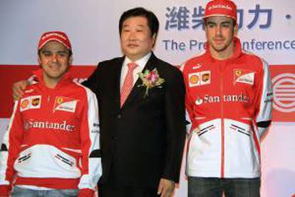 Los pilotos de Ferrari Felipe Massa (i) y Fernando Alonso (d) posan junto a Tan Xuguang, presidente ejecutivo de Weichai Power, durante la presentación de la alianza publicitaria entre la firma china y la escudería en Shanghái.