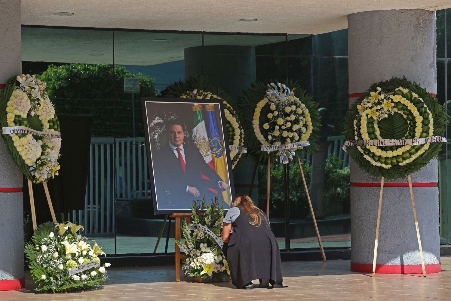 Una mujer coloca un par de veladoras al pie del altar que fue instalado en el  funeral Jorge Aristóteles Sandoval Díaz.