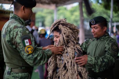 Elementos del Ejército Mexicano colocan un traje de camuflaje a un niño.