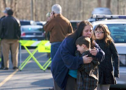 Un alumno del colegio es consolado por una mujer a las puertas del colegio Sandy Hook
