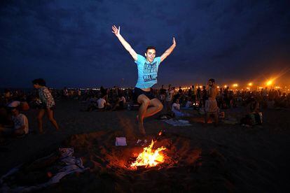 Un joven salta una hoguera en la playa de La Malvarrosa en Valencia.