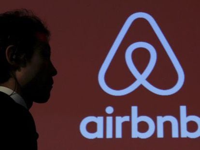Un hombre pasea junto a un logotipo de Airbnb.