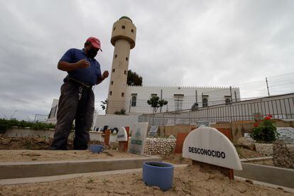 Un trabajador del cementerio musulmán de Melilla reza ante la tumba de una persona migrante desconocida, el pasado mayo.