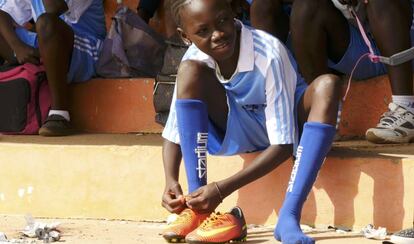 Una joven jugadora de fútbol gambiana se ata las botas.