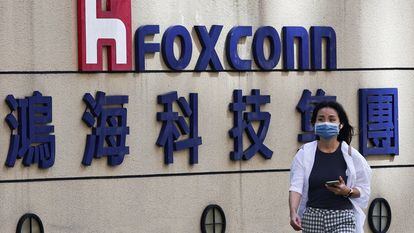 Una mujer pasa junto al logotipo de Foxconn en el exterior del edificio de la empresa en Taipei, Taiwán.