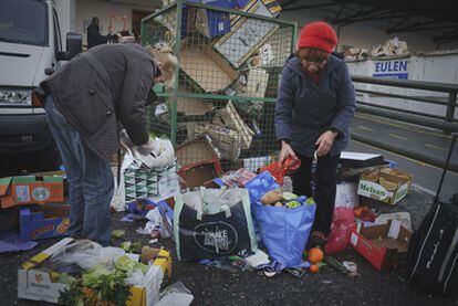 Dos personas recogen comida de la basura en Madrid, en diciembre.